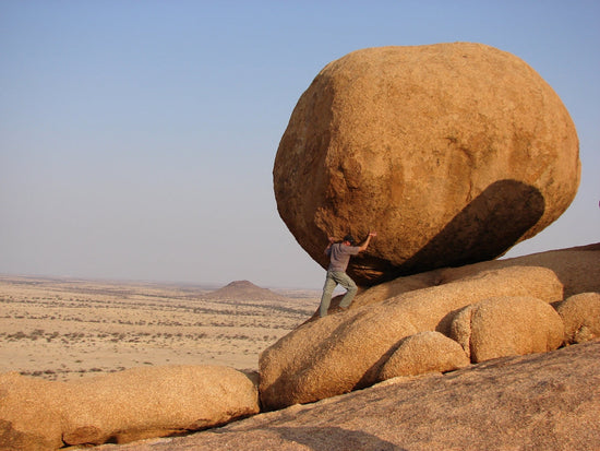 man standing beside rock formation sustainable training programs for lasting strength. 