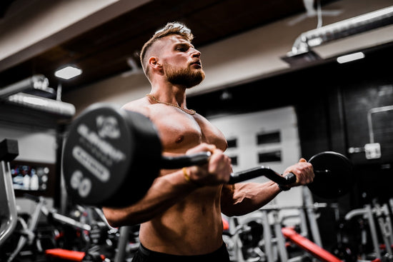 topless man in black shorts carrying black dumbbell. premium bodybuilding supplements