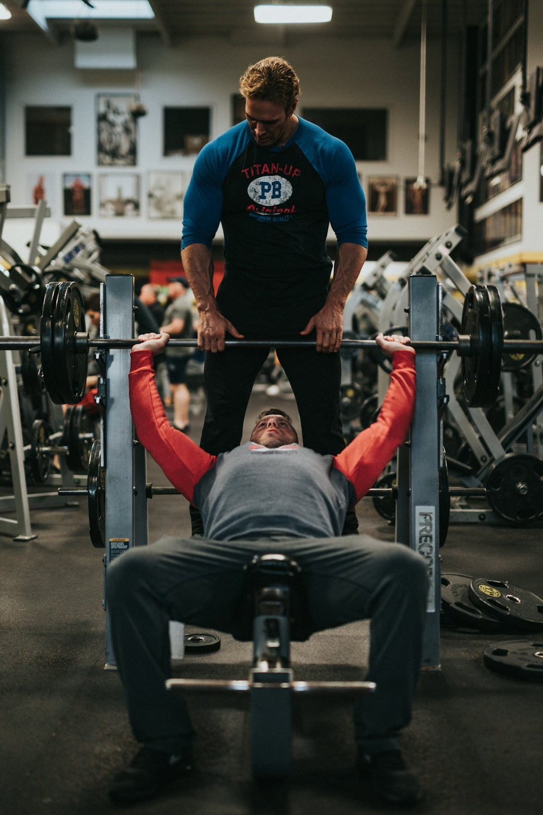 man in black crew neck t-shirt and gray pants sitting on black and red bench. BCAA post-workout powder for recovery