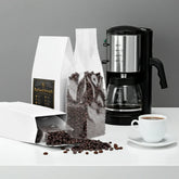 BigSouthStrength coffee beans in white bags, coffee maker, and brewed cup for pre-workout energy