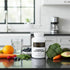 Complete Multivitamin capsules with fresh fruits, veggies, and water on kitchen counter for daily wellness