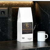 Vitality Mushroom Coffee Medium Roast bag beside white mug on black marble countertop